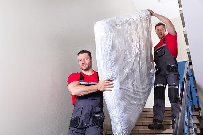 team of workers maneuvering a box spring through a doorway in Auburn